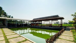Piscina con muelle de madera y pabellón cubierto.