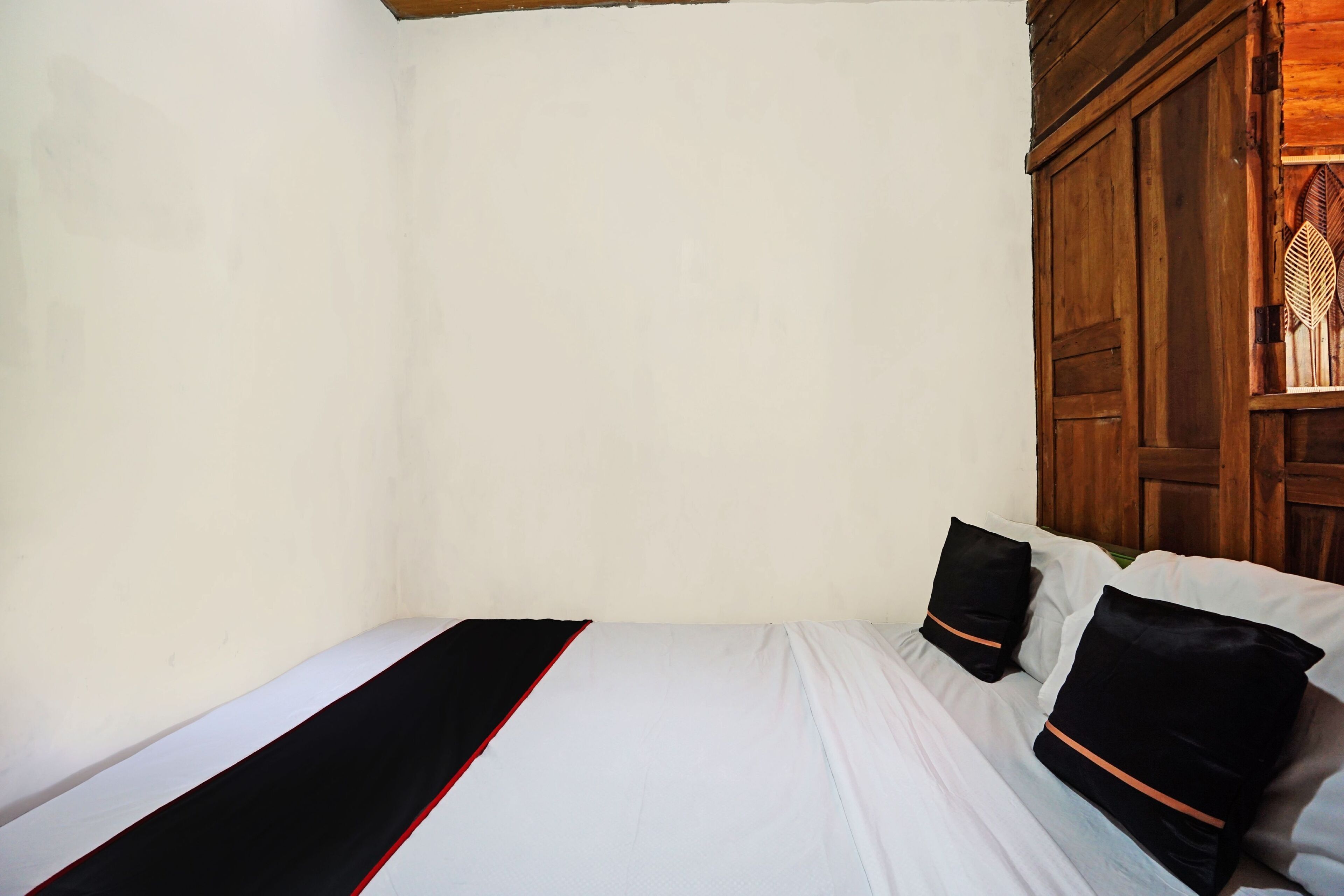 A simple room with a bed, two pillows, and a wooden wardrobe.