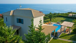 Eine Villa mit Swimmingpool, Außenbereich zum Sitzen und Meerblick.