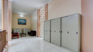 A hotel lobby with lockers, a painting on the wall, and a seating area. - Hotel O Guest House Mulia Dua Syariah (Klaten)