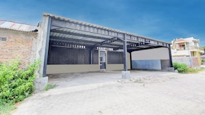 A covered parking area with a metal roof, a concrete pillar, and a brick wall. - Hotel O Guest House Mulia Dua Syariah (Klaten)