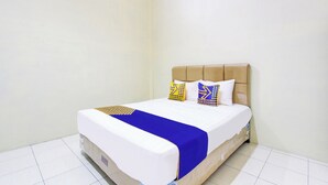 A neatly made bed with a blue and white bedspread, two patterned pillows, and a wooden headboard. - Hotel O Guest House Mulia Dua Syariah (Klaten)