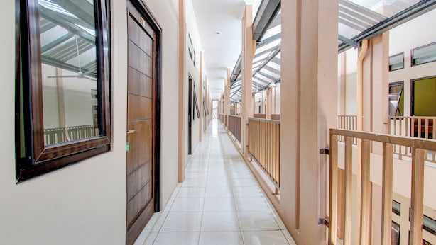 A corridor with a tiled floor, wooden doors, and a glass ceiling. - Hotel O Guest House Mulia Dua Syariah (Klaten)