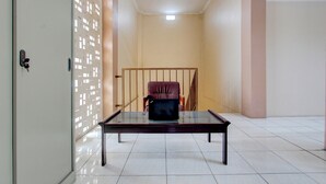 A room with a glass-top table, a red chair, and a door with a key lock. - Hotel O Guest House Mulia Dua Syariah (Klaten)