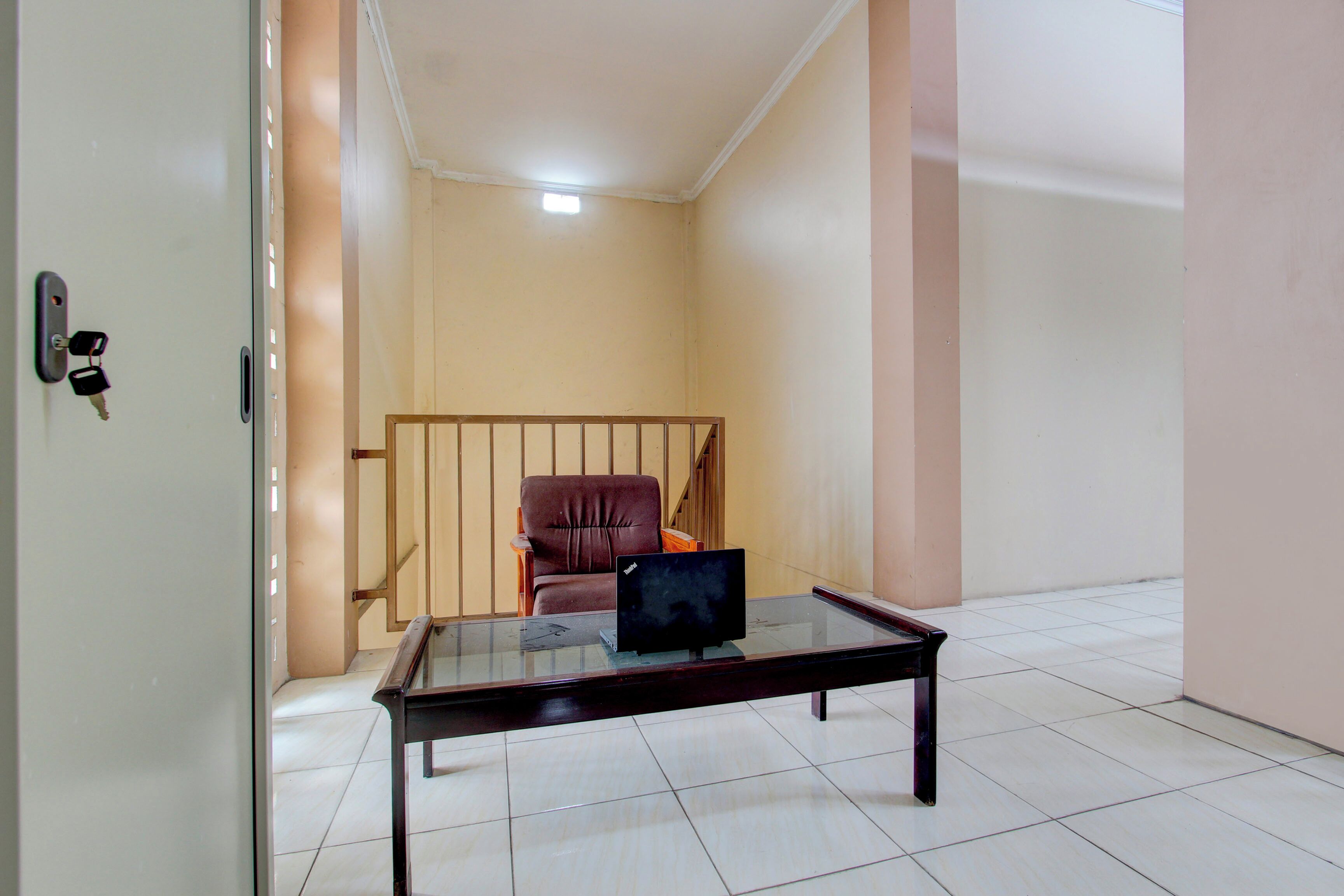 A room with a glass-top table, a brown leather chair, and a television.