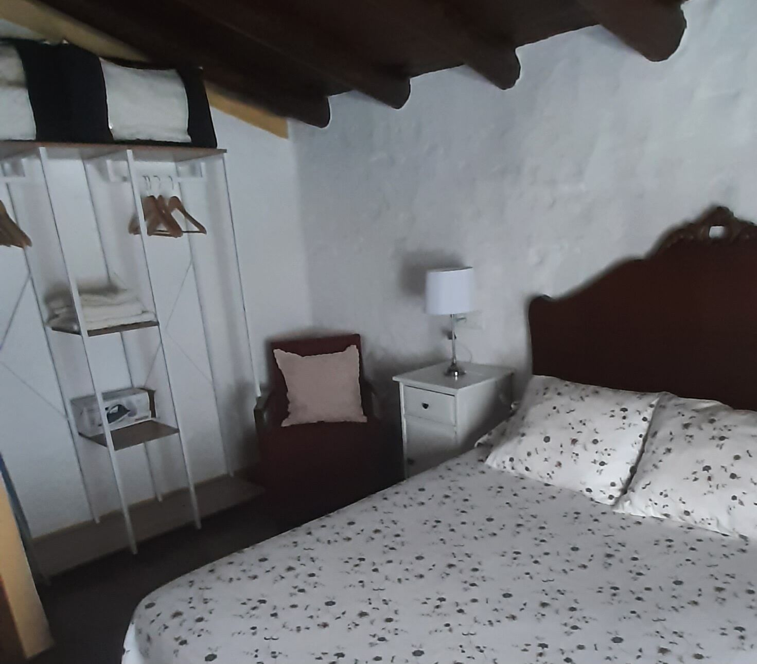 A bedroom with a bed, a nightstand, a chair, and a wardrobe.