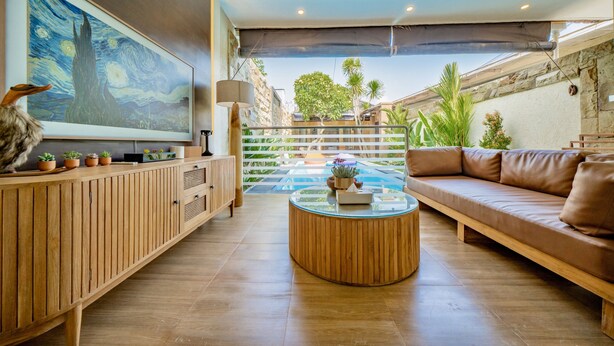 A modern living room with a wooden cabinet, a round coffee table, a brown sofa, and a large painting on the wall.