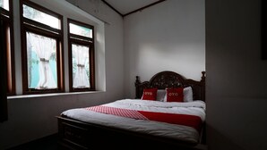 A bedroom with a single bed, a window with curtains, and a wooden headboard. - OYO 93248 Villa Syariah Astuti Lestari (Parongpong)