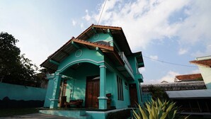 A two-story house with a tiled roof and a porch. - OYO 93248 Villa Syariah Astuti Lestari (Parongpong)