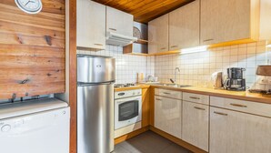 A kitchen with wooden cabinets, a stainless steel refrigerator, an oven, a sink, and a coffee maker. - Cozy 1BR+Alcove in Serre Chevalier with Pool, WiFi, Private Parking, Near Slopes (Saint-Chaffrey)