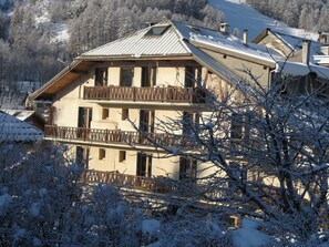 Ein mehrstöckiges Gebäude mit Balkonen, umgeben von schneebedeckten Bäumen.