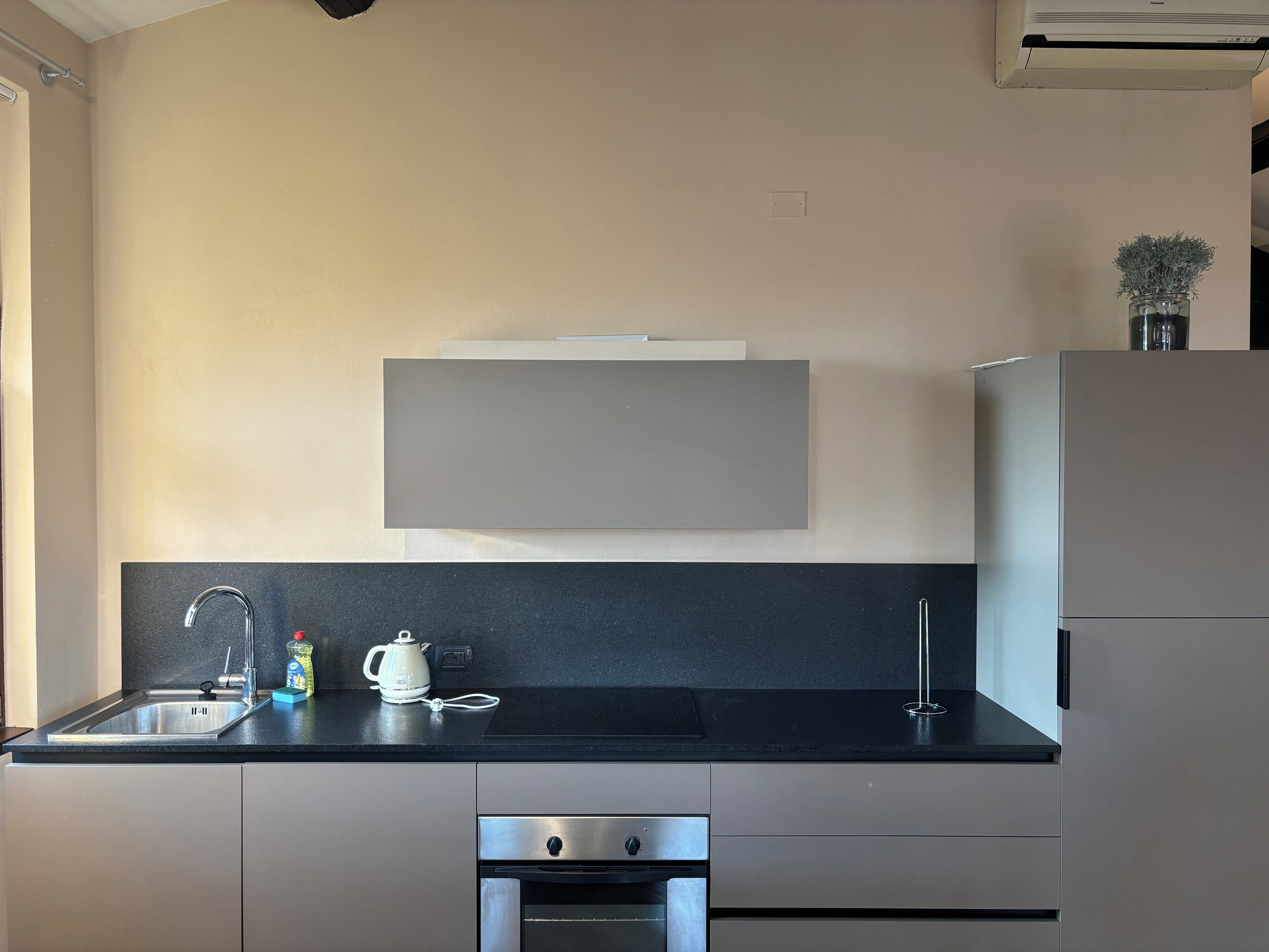 A modern kitchen with a black countertop, stainless steel appliances, and a minimalist design.