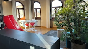 A modern living room with a red chair, a white table, and a large potted plant. - Piazza Erbe Lodge (Verona)
