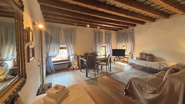 A room with a bed, a sofa, a desk with a chair, a television, and a window with curtains. - Piazza Erbe Lodge (Verona)