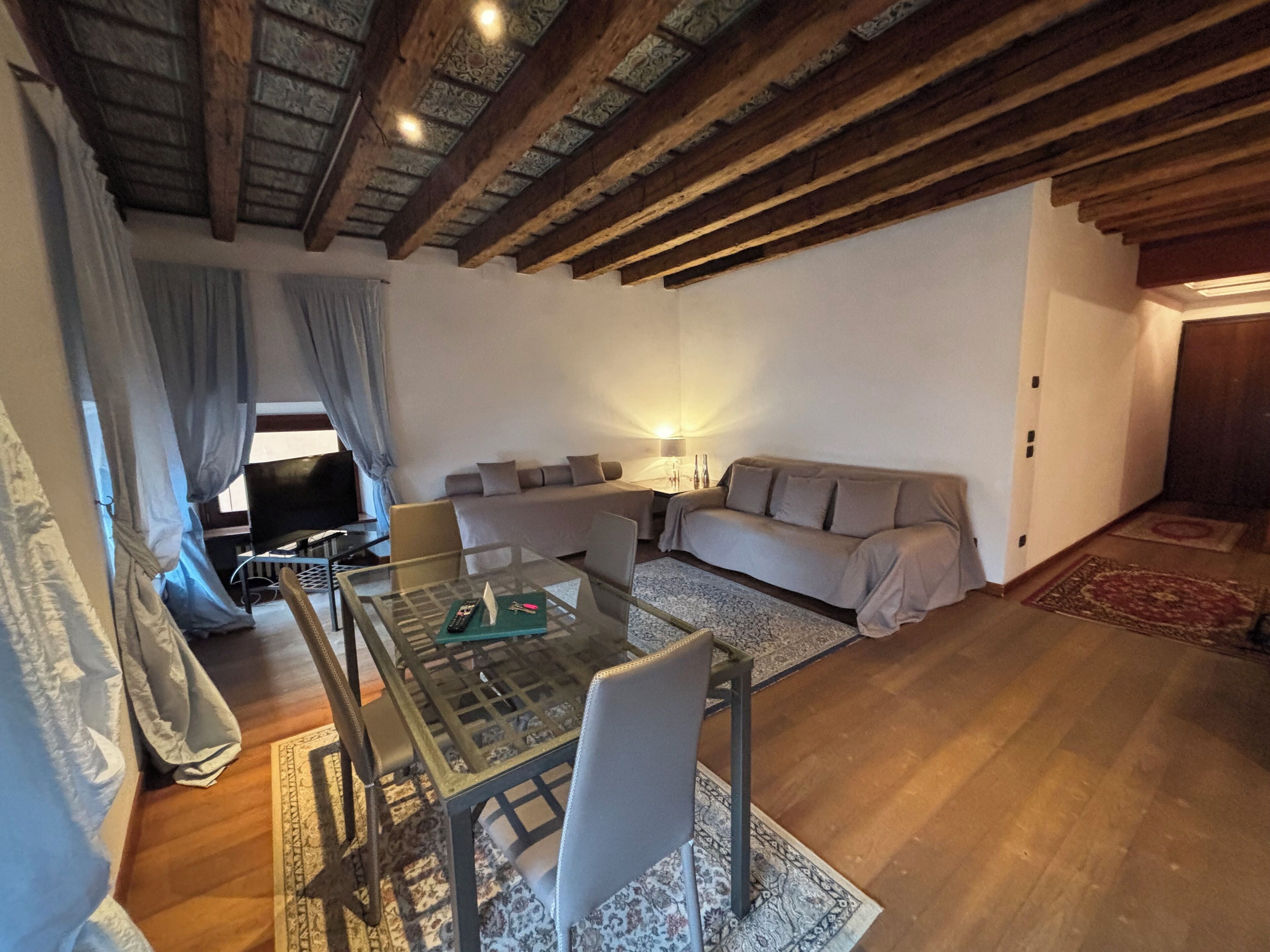 A cozy living room with a glass coffee table, a sofa, and a TV.