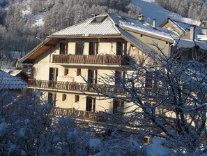 A multi-story building with balconies, surrounded by snow-covered trees.