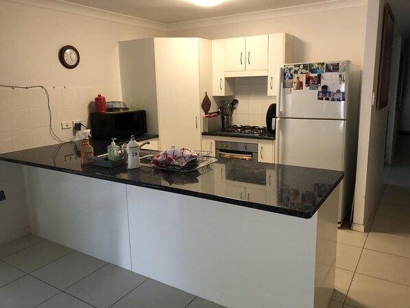 A kitchen with white cabinets, a black countertop, a microwave, a stove, and a refrigerator with photos on it.