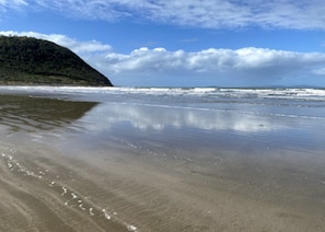 A beach with a sandy shore and a hill in the background.