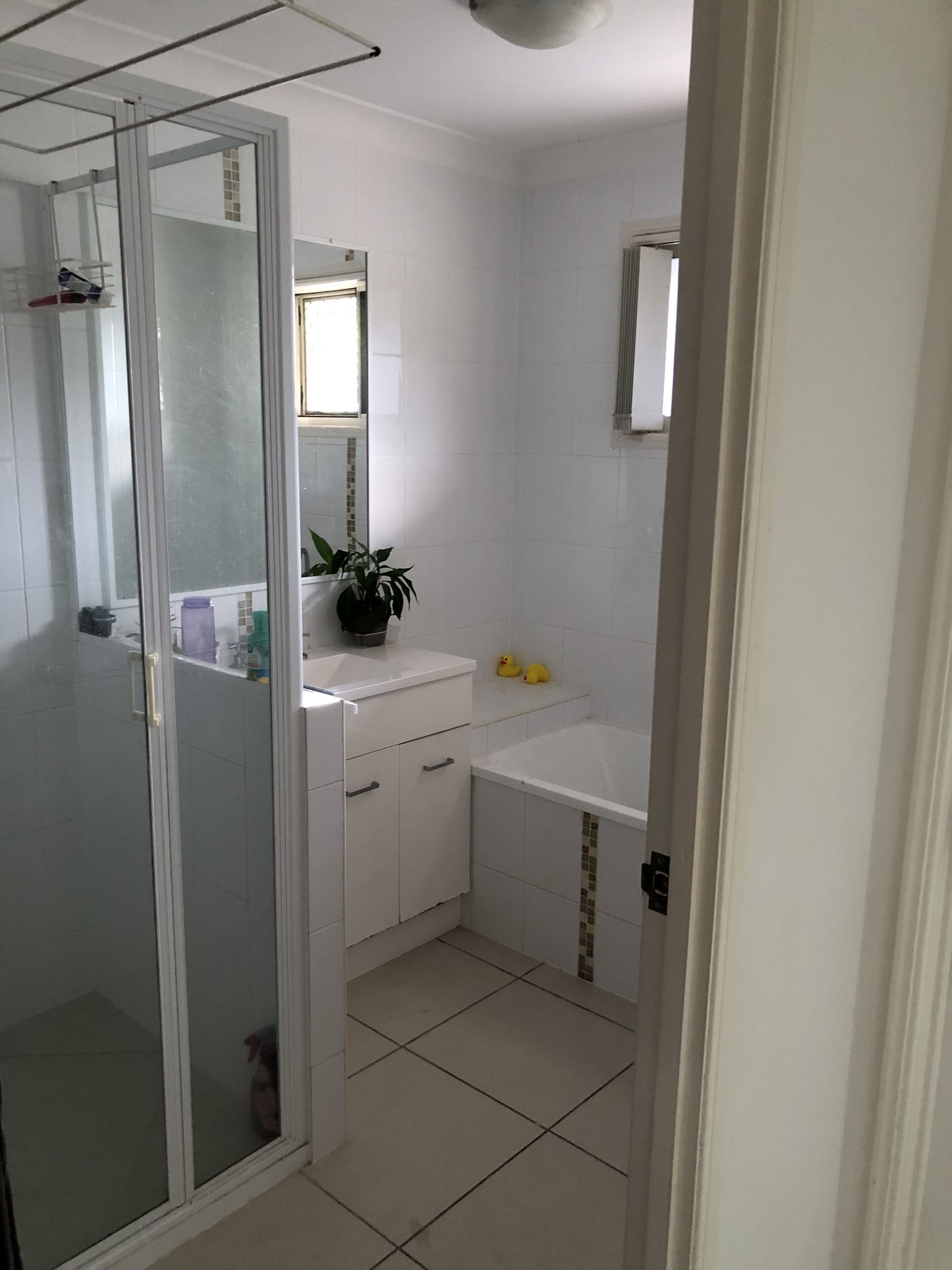 Un baño con cabina de ducha de vidrio, un lavabo blanco y un espejo encima.