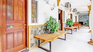 A hallway with wooden benches, a stone wall, and a wooden door with a number plaque.