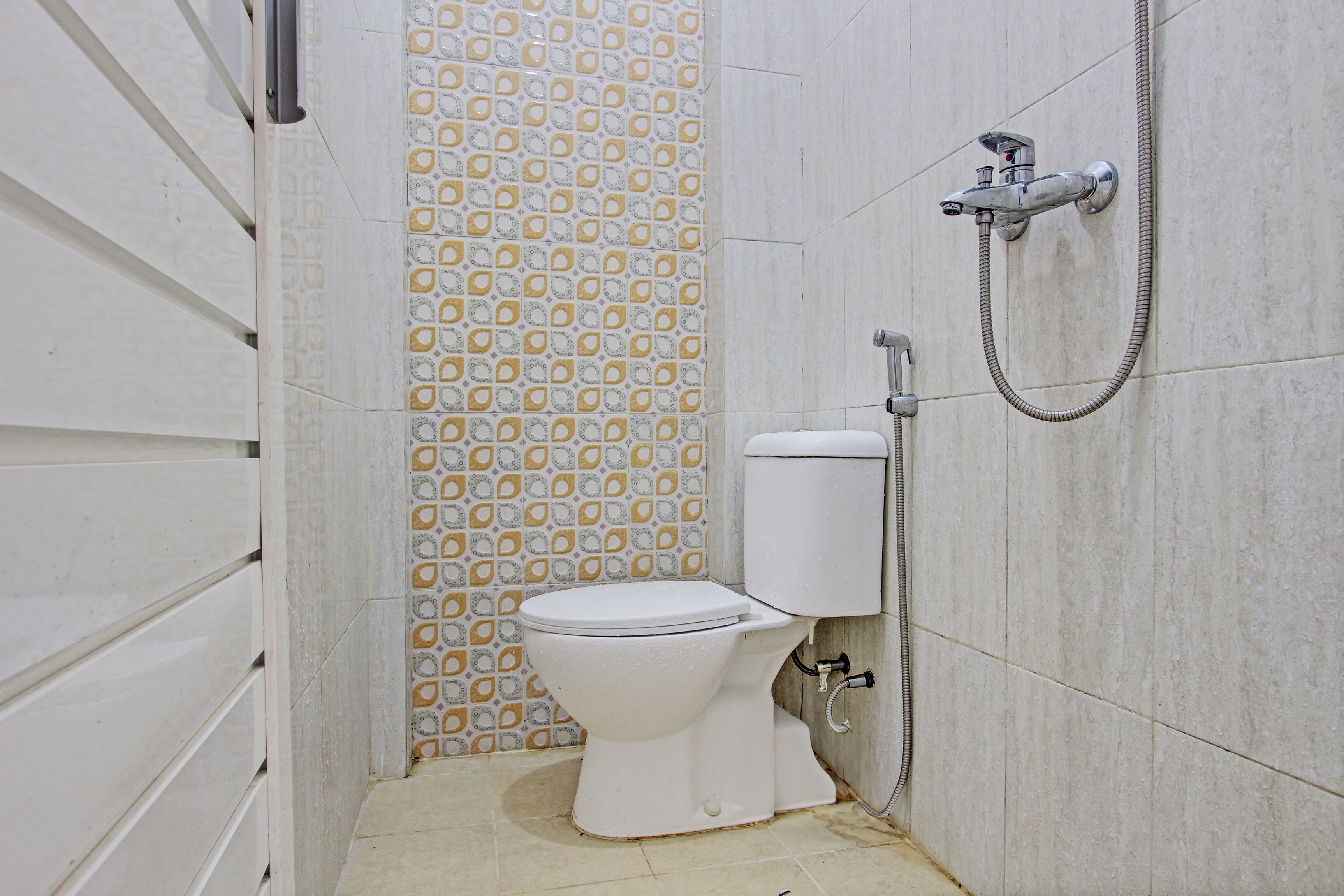 Een compacte badkamer met toilet, douche en een behang met patroon.