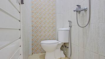 Een compacte badkamer met toilet, douche en een behang met patroon.
