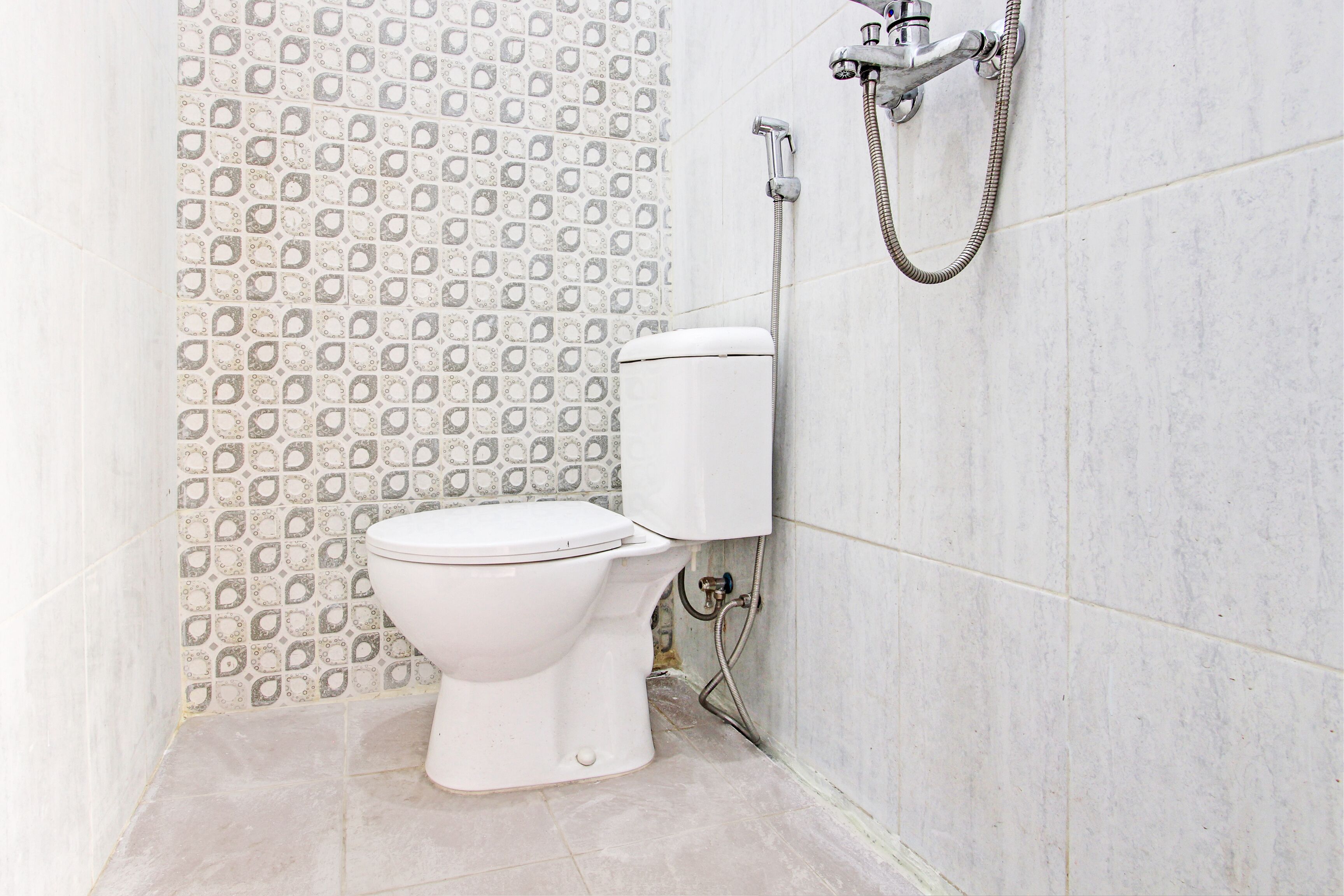 A bathroom with a toilet, a shower, and patterned tiles.
