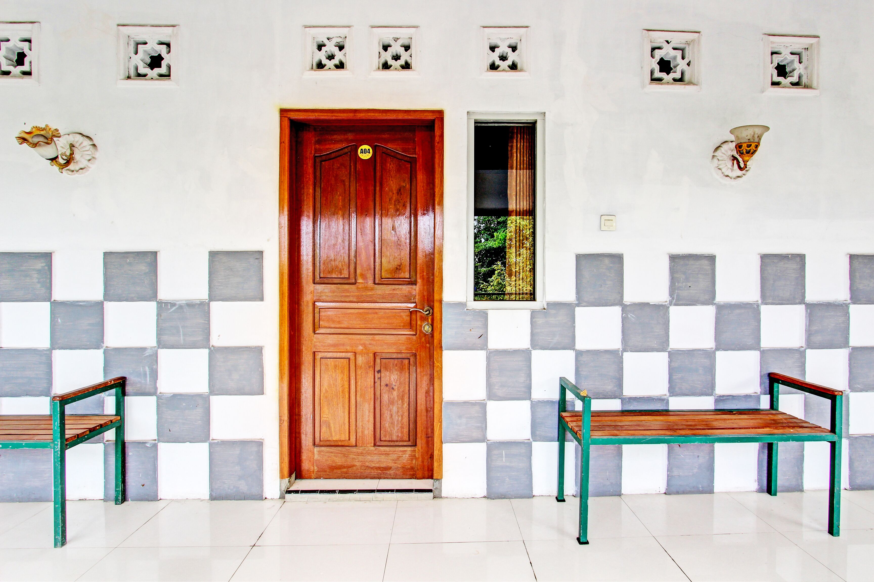 A room with a wooden door, checkered wall tiles, and two benches.
