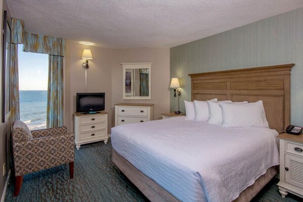 Relax in comfort with a large bed, two nightstands, a television, and a cozy armchair, all offering a view of the ocean.