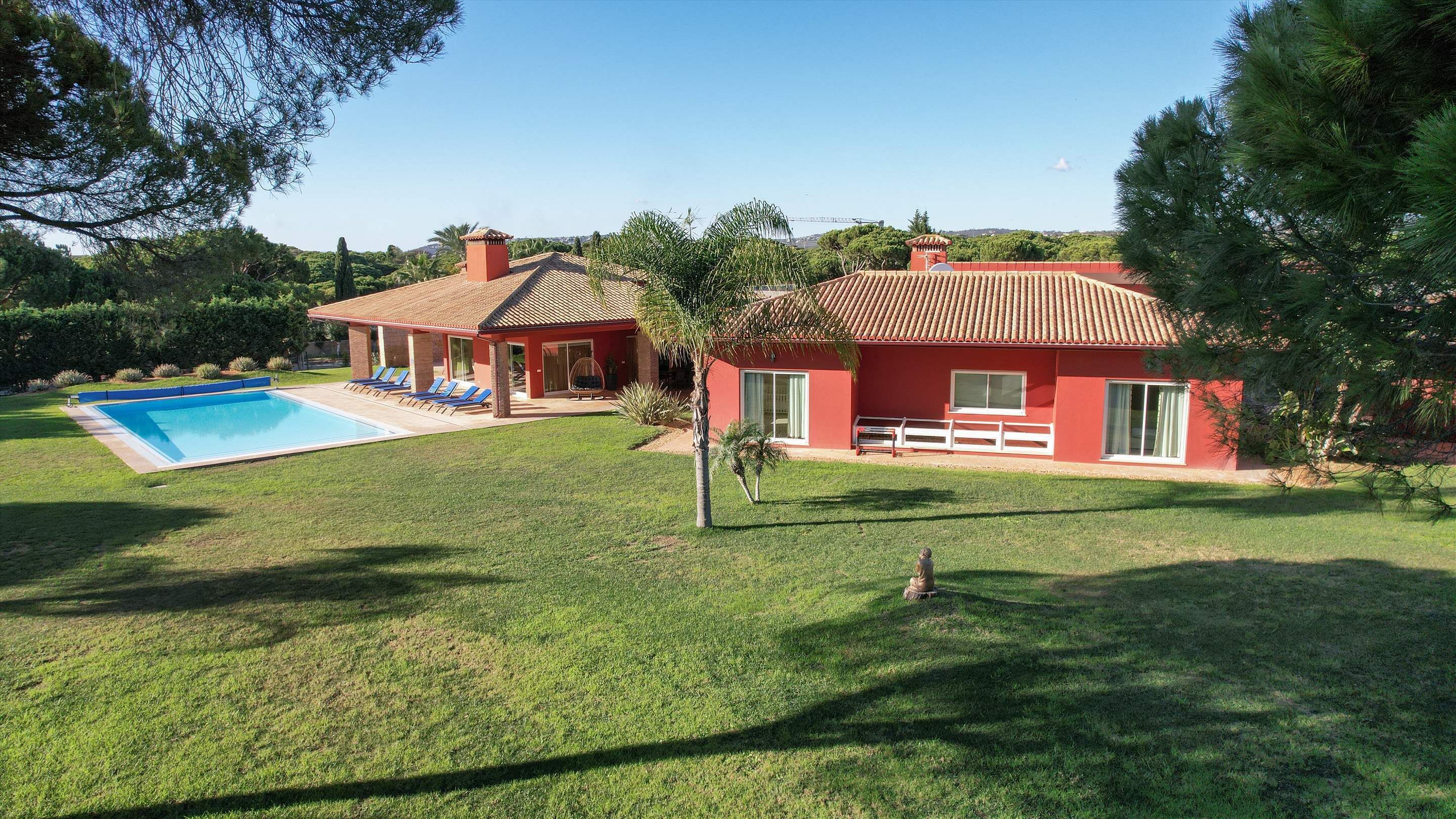 A house with a swimming pool, a red exterior, and a well-maintained lawn.