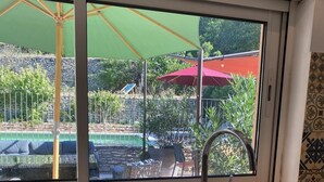 A kitchen with a large window, a sink, and a view of a pool and outdoor seating area. - Maison Provençale Avec Grande Piscine à Goult en Plein Coeur du Luberon (Goult)