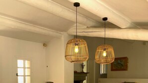 A dining area with a wooden table and white chairs, two hanging wicker lamps, and a white radiator. - Maison Provençale Avec Grande Piscine à Goult en Plein Coeur du Luberon (Goult)