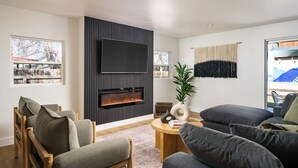 A modern living room with a fireplace, comfortable seating, and a large TV. - Spacious + Stylish Home w/HotTub 12min to Downtown (Westminster)