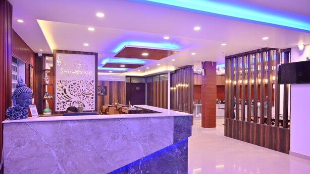 Una zona de recepción moderna con mostrador de mármol, elementos decorativos e iluminación azul en el techo.