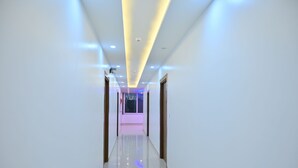 Un pasillo moderno de hotel con piso brillante, iluminación empotrada y vista nocturna de la ciudad.
