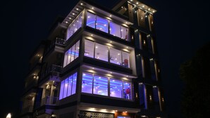 Un edificio moderno de varios pisos con ventanas e balcones iluminados.