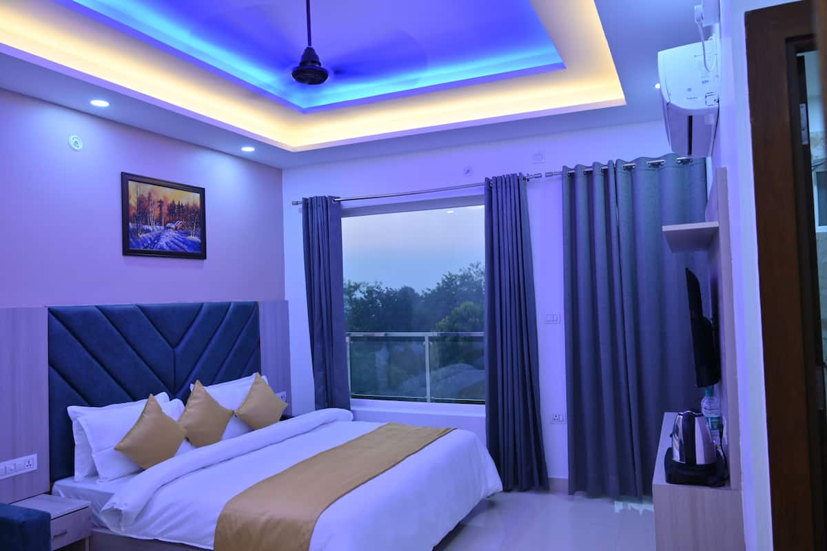 Habitación de hotel moderna con una cama grande, vistas al exterior e iluminación azul en el techo.