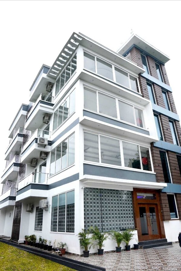 A multi-story building with balconies, large windows, and a patterned entrance.