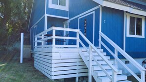 Un edificio azul con una escalera blanca que conduce a un porche cubierto.