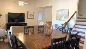 Un comedor con una mesa y sillas de madera, un televisor y obras de arte en las paredes.
