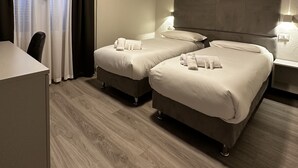 A hotel room with two beds, a desk, and a television. - Hotel l'Etrusco - San Vincenzo (San Vincenzo)