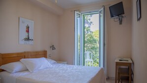 A bedroom with a bed, a desk, a chair, a TV, and a window with a view of trees. - Hotel l'Etrusco - San Vincenzo (San Vincenzo)