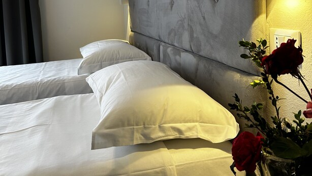 A hotel room with a large bed, a bedside table, and a vase with a red rose. - Hotel l'Etrusco - San Vincenzo (San Vincenzo)