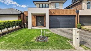 Een modern huis met twee verdiepingen, een garage, een verzorgd gazon en een brievenbus.
