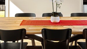 Een vergaderruimte met een houten tafel, zwarte stoelen, een klok aan de muur en een potorkidee op de tafel.
