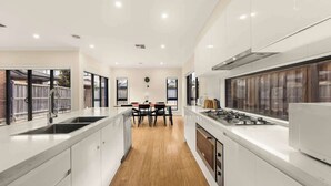 Een moderne keuken met een centraal eiland, een eethoek en uitzicht door grote ramen.