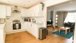 Une cuisine moderne avec des armoires blanches, une hotte de cuisinière en acier inoxydable et un lave-vaisselle compact.