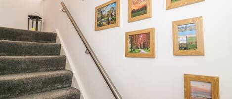 A staircase with a handrail leading to a landing where multiple framed pictures are hung on the wall.