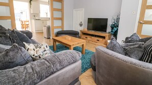 Un salon moderne avec des canapés gris, une table basse en bois et un téléviseur posé sur un meuble en bois.