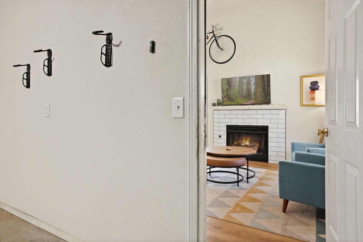 A modern living room with a fireplace, a dining area with a round table, and a blue sofa.